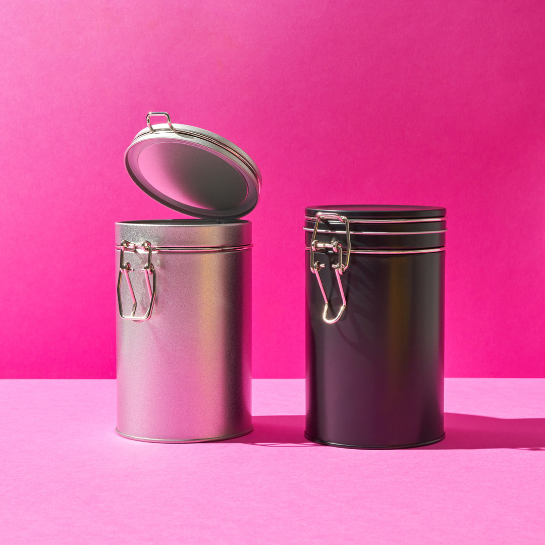 A picture of two clip lid tins, one black and one silver. The clips on the tins are also silver.