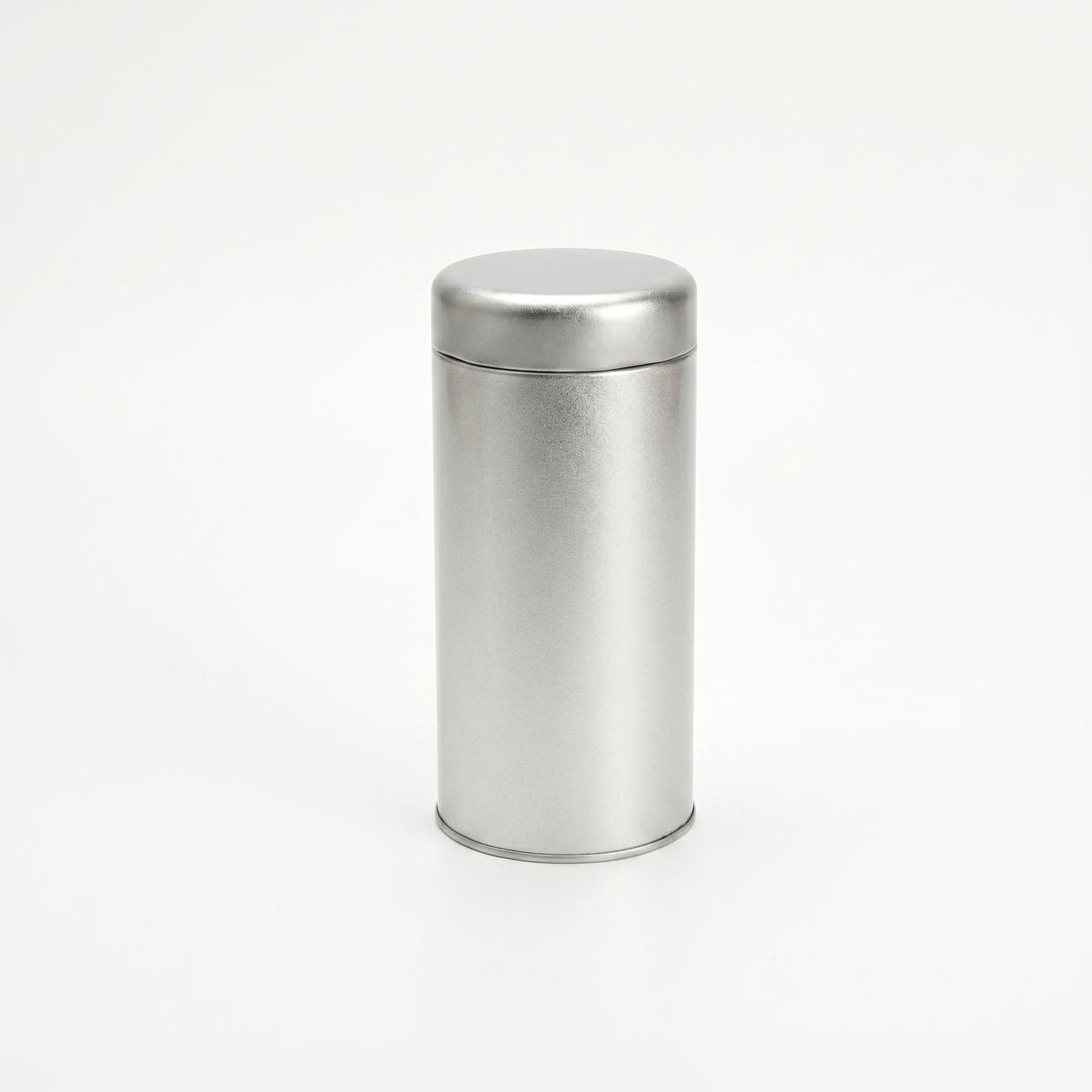 Round silver tea tin with slip lid standing upright on white background.